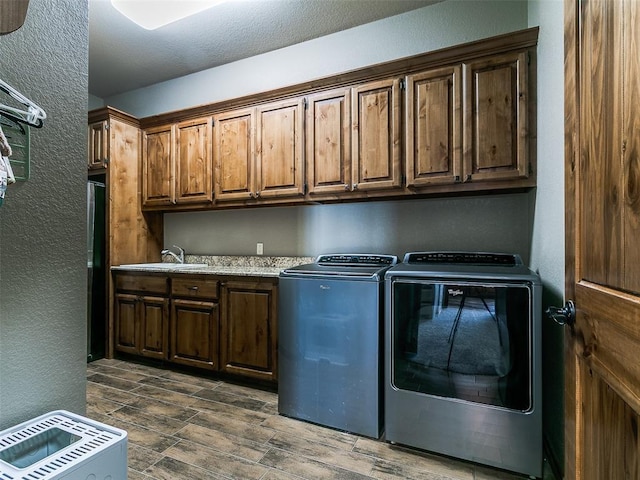 12905 S Mustang Rd, Mustang, OK 73064 - laundry room with cabinet space, washer and clothes dryer, a textured wall, and wood tiled floors
