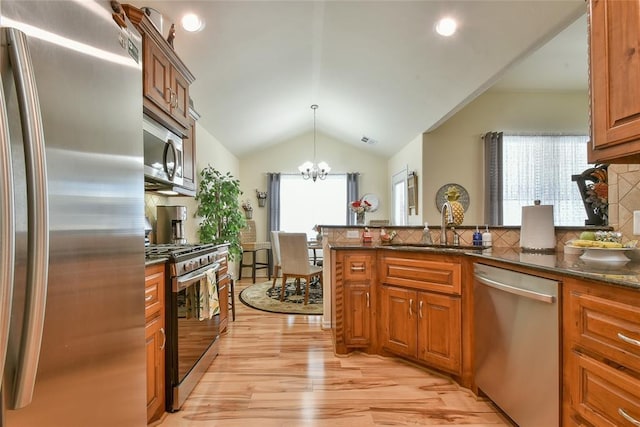 2221 NW 158th St, Edmond, OK 73013 - kitchen featuring appliances with stainless steel finishes, lofted ceiling, a chandelier, light wood-type flooring, and brown cabinets