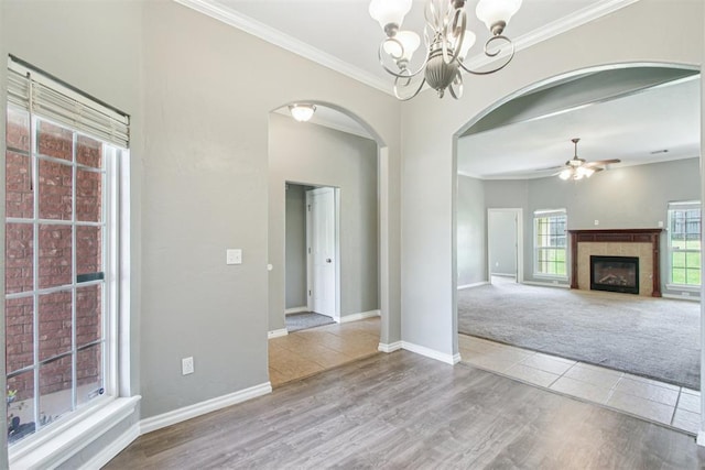 4605 Mackenzie Dr, Moore, OK 73160 - unfurnished living room with arched walkways, a chandelier, crown molding, a fireplace, and wood finished floors