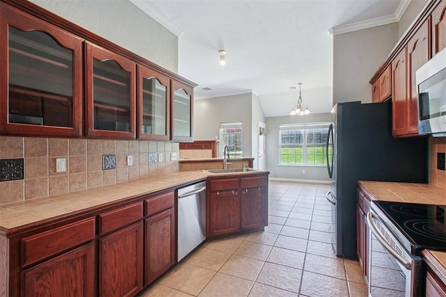 4605 Mackenzie Dr, Moore, OK 73160 - kitchen featuring appliances with stainless steel finishes, tile countertops, backsplash, a chandelier, and light tile patterned flooring