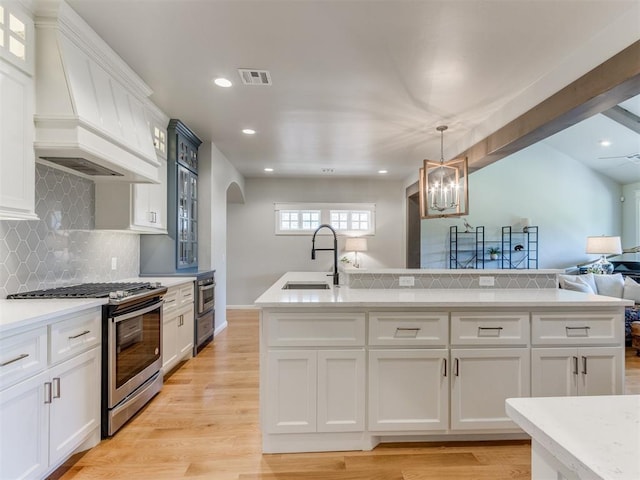 3508 Pavilion Pl, Edmond, OK 73034 - kitchen with stainless steel range with gas cooktop, arched walkways, open floor plan, light wood-style floors, and light countertops
