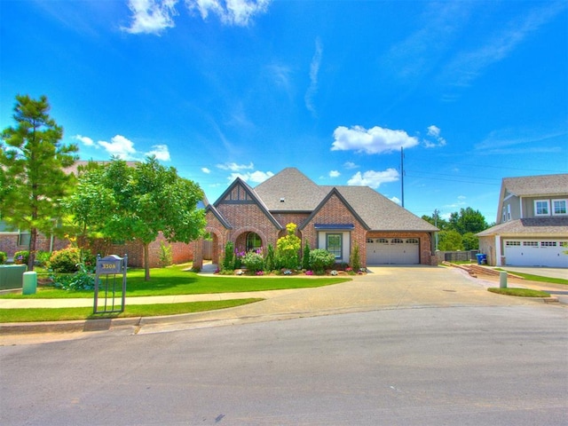3508 Pavilion Pl, Edmond, OK 73034 - tudor-style house featuring driveway, brick siding, a garage, and a front lawn