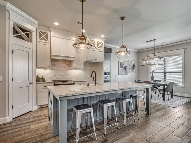 4821 Hidalgo Ave, Mustang, OK 73064 - kitchen featuring dark wood-type flooring, white cabinets, light stone counters, ornamental molding, and a kitchen breakfast bar