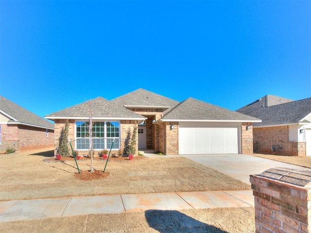 9313 NW 141st St, Yukon, OK 73099 - view of front facade featuring a garage, driveway, brick siding, and a shingled roof