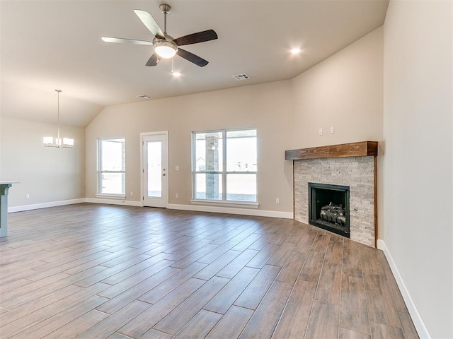 9313 NW 141st St, Yukon, OK 73099 - unfurnished living room featuring a stone fireplace, a chandelier, vaulted ceiling, wood finished floors, and ceiling fan