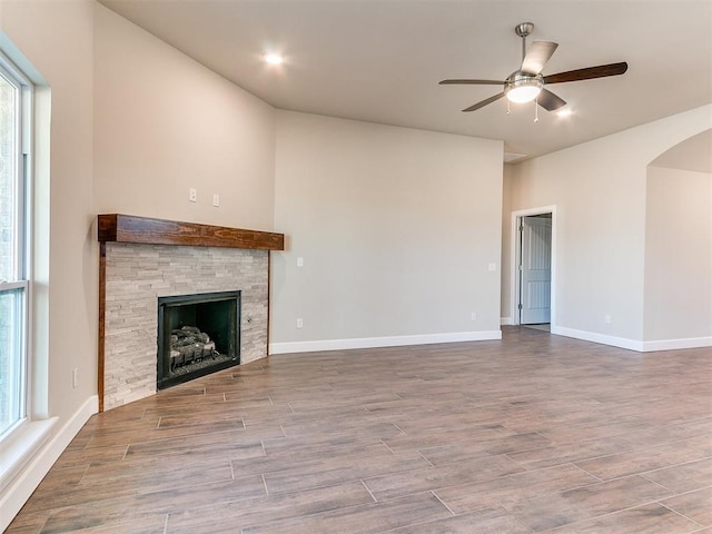 9313 NW 141st St, Yukon, OK 73099 - unfurnished living room featuring ceiling fan, a fireplace, wood finished floors, arched walkways, and lofted ceiling