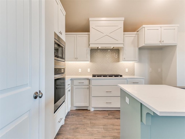 9313 NW 141st St, Yukon, OK 73099 - kitchen with stainless steel appliances, tasteful backsplash, white cabinetry, light countertops, and premium range hood