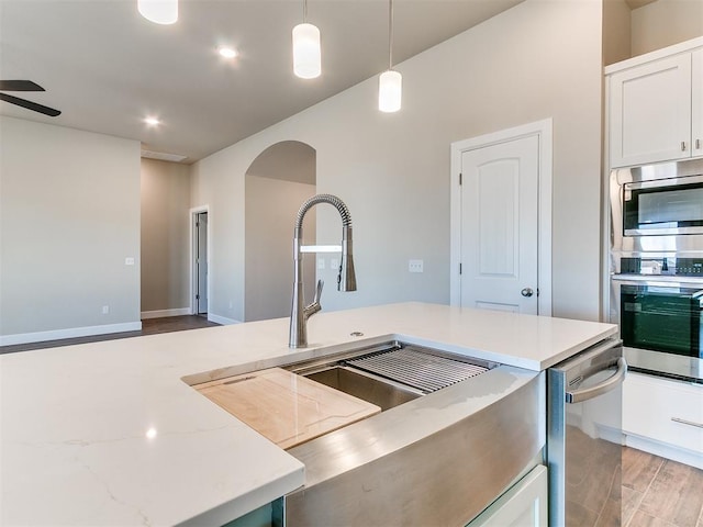 9313 NW 141st St, Yukon, OK 73099 - kitchen with stainless steel appliances, arched walkways, pendant lighting, white cabinets, and light stone counters