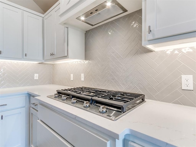 9313 NW 141st St, Yukon, OK 73099 - kitchen with wall chimney range hood, stainless steel gas stovetop, tasteful backsplash, and white cabinetry