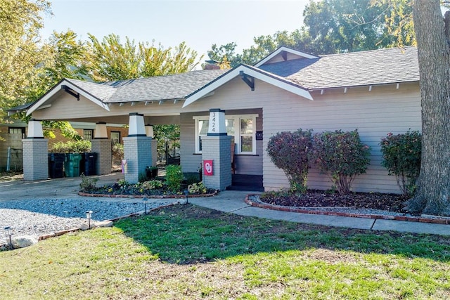 3424 NW 16th St, Oklahoma City, OK 73107 - view of front facade with covered porch, a shingled roof, a front lawn, and driveway