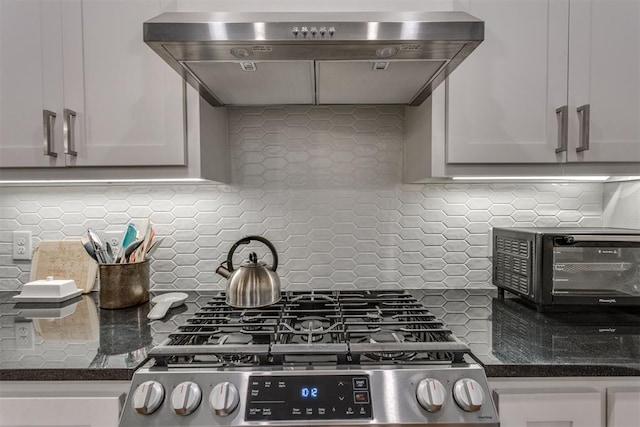 3424 NW 16th St, Oklahoma City, OK 73107 - kitchen featuring wall chimney range hood, stainless steel gas range, backsplash, dark stone counters, and white cabinetry