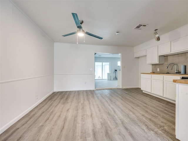 6908 NW 36th St, Bethany, OK 73008 - kitchen with light wood-style floors, a ceiling fan, backsplash, white cabinetry, and light countertops