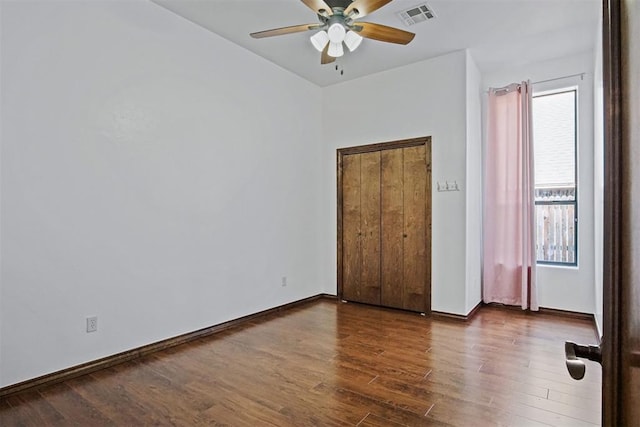 917 Erinova Dr, Yukon, OK 73099 - unfurnished bedroom with multiple windows, dark wood-style floors, and ceiling fan