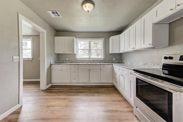 5417 NW 45th Ter, Warr Acres, OK 73122 - kitchen with stainless steel electric stove, white cabinets, light wood-type flooring, and light stone counters