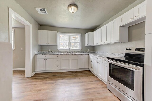 5417 NW 45th Ter, Warr Acres, OK 73122 - kitchen with stainless steel electric range, white cabinets, light wood finished floors, and light stone countertops
