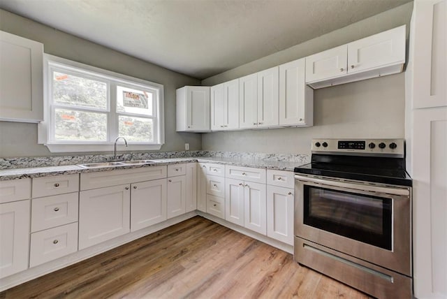 5417 NW 45th Ter, Warr Acres, OK 73122 - kitchen with stainless steel range with electric stovetop, light wood-type flooring, white cabinets, and light stone countertops
