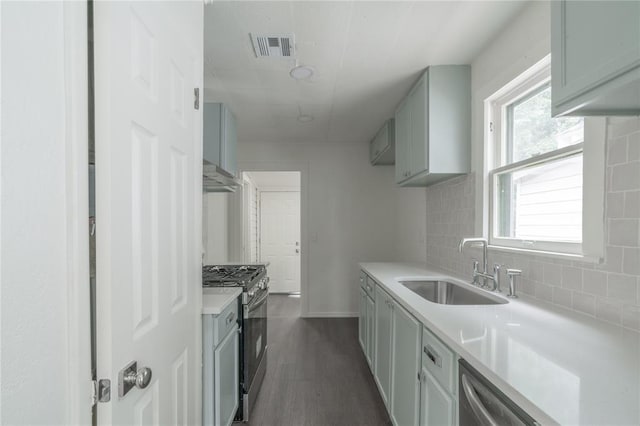 2220 SW 28th St, Oklahoma City, OK 73108 - kitchen with stainless steel appliances, tasteful backsplash, under cabinet range hood, light countertops, and dark wood-style flooring