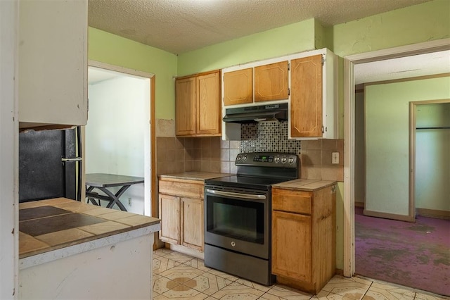 2120 E Robberts Ave, Kingfisher, OK 73750 - kitchen featuring stainless steel electric range oven, tile countertops, under cabinet range hood, a textured ceiling, and decorative backsplash