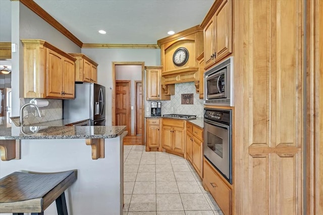 1716 NW 182nd St, Edmond, OK 73012 - kitchen with stainless steel appliances, a peninsula, a kitchen breakfast bar, light tile patterned floors, and dark stone countertops