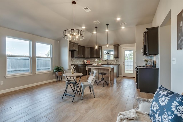 6420 SE 88th St, Oklahoma City, OK 73135 - kitchen with a center island, light wood-style flooring, decorative backsplash, a kitchen breakfast bar, and range with gas stovetop