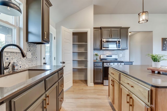6420 SE 88th St, Oklahoma City, OK 73135 - kitchen featuring appliances with stainless steel finishes, decorative backsplash, light wood-type flooring, dark countertops, and lofted ceiling