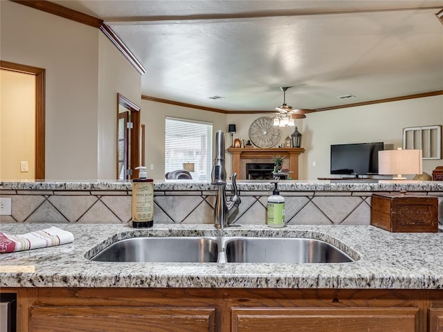 9021 NW 81st St, Yukon, OK 73099 - kitchen featuring crown molding, ceiling fan, open floor plan, a fireplace, and light stone counters
