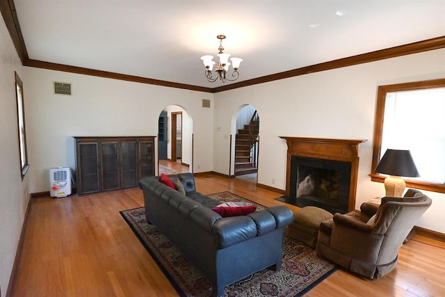 1712 W University Ave, Stillwater, OK 74074 - living area featuring arched walkways, wood finished floors, a chandelier, a fireplace with flush hearth, and ornamental molding
