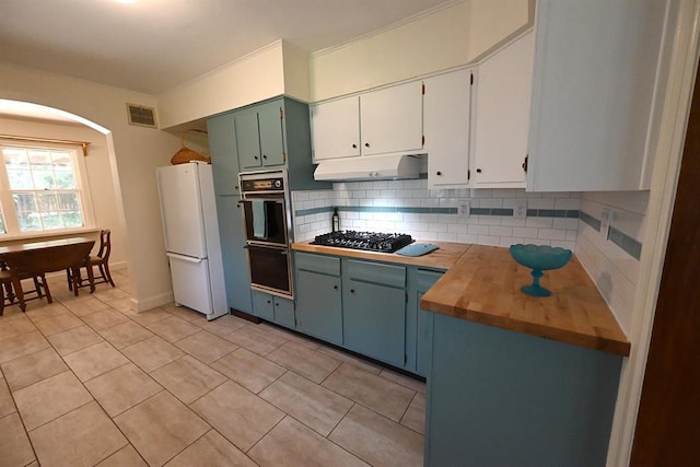 1712 W University Ave, Stillwater, OK 74074 - kitchen featuring freestanding refrigerator, gas stovetop, tasteful backsplash, under cabinet range hood, and arched walkways