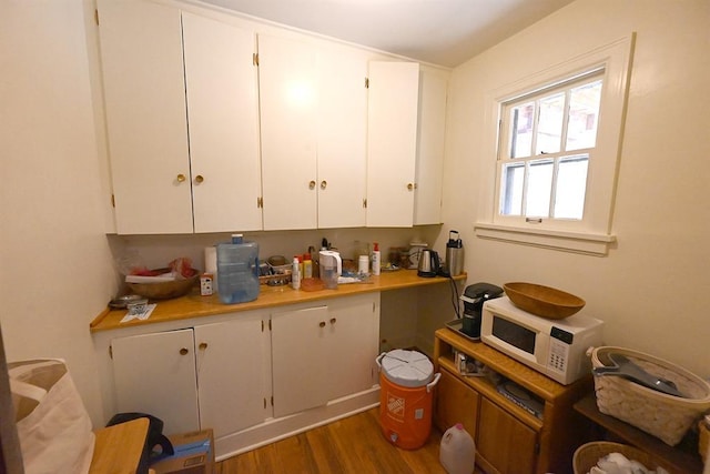 1712 W University Ave, Stillwater, OK 74074 - kitchen featuring white microwave, white cabinets, light countertops, and wood finished floors