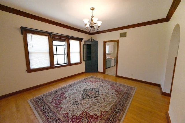1712 W University Ave, Stillwater, OK 74074 - spare room featuring arched walkways, a chandelier, light wood-type flooring, and crown molding