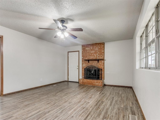 5901 Seminole Rd, Warr Acres, OK 73132 - unfurnished living room featuring wood finished floors, a textured ceiling, a ceiling fan, and a brick fireplace