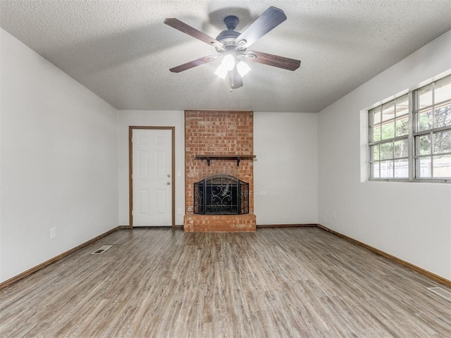 5901 Seminole Rd, Warr Acres, OK 73132 - unfurnished living room with wood finished floors, a fireplace, a textured ceiling, and a ceiling fan