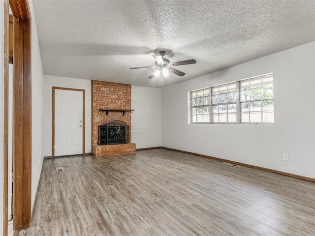 5901 Seminole Rd, Warr Acres, OK 73132 - unfurnished living room with wood finished floors, ceiling fan, a fireplace, and a textured ceiling