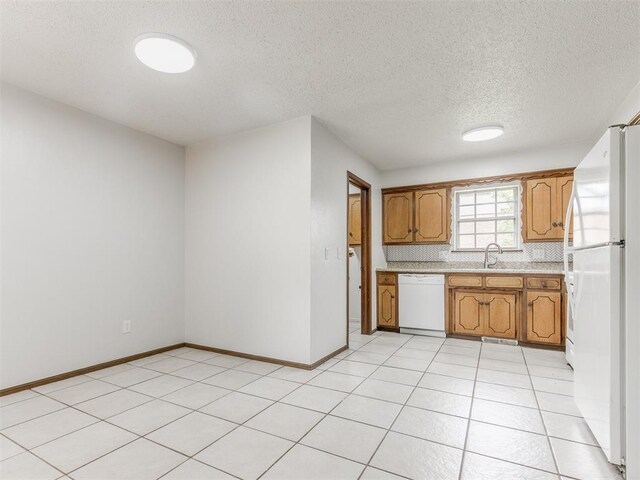 5901 Seminole Rd, Warr Acres, OK 73132 - kitchen with white appliances, light countertops, a textured ceiling, brown cabinets, and light tile patterned floors