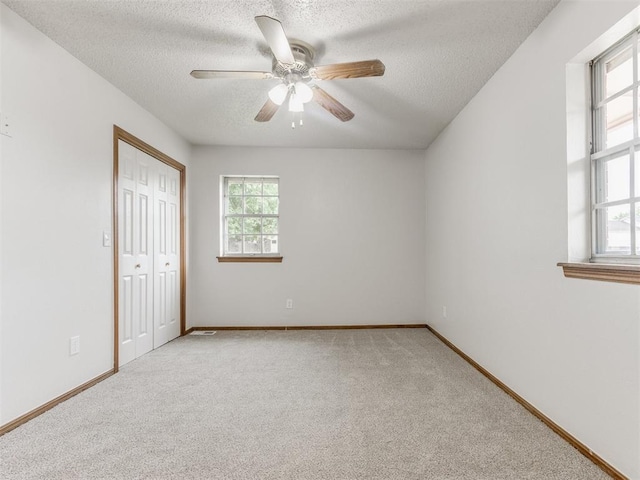 5901 Seminole Rd, Warr Acres, OK 73132 - unfurnished bedroom featuring a textured ceiling, light carpet, a closet, and a ceiling fan