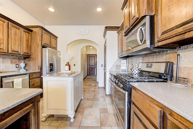 921 Tea Rose Dr, Yukon, OK 73099 - kitchen featuring stainless steel appliances, arched walkways, backsplash, recessed lighting, and brown cabinets