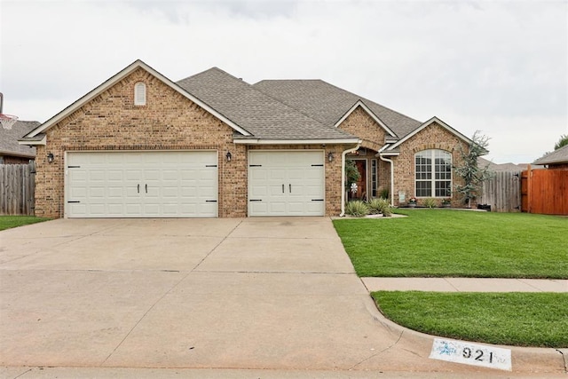 921 Tea Rose Dr, Yukon, OK 73099 - view of front facade with concrete driveway, brick siding, a garage, and roof with shingles
