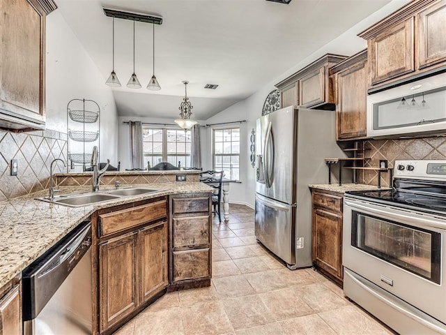 516 SW 161st St, Oklahoma City, OK 73170 - kitchen featuring stainless steel appliances, tasteful backsplash, lofted ceiling, a peninsula, and hanging light fixtures