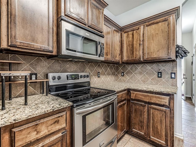 516 SW 161st St, Oklahoma City, OK 73170 - kitchen featuring stainless steel appliances, decorative backsplash, light stone counters, and light tile patterned flooring