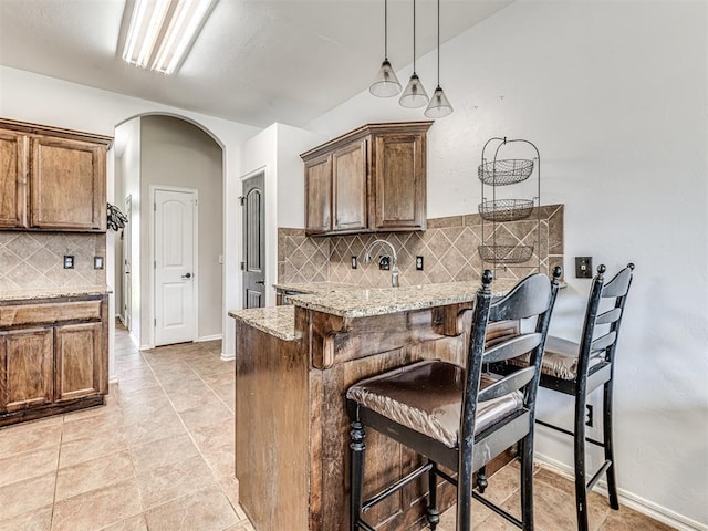 516 SW 161st St, Oklahoma City, OK 73170 - kitchen with tasteful backsplash, a breakfast bar, arched walkways, light stone countertops, and a peninsula