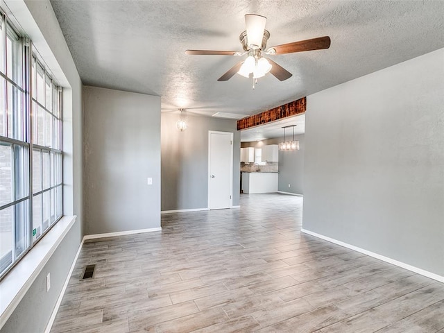 1917 Barryton Rd, Oklahoma City, OK 73120 - spare room with ceiling fan, a textured ceiling, light wood-type flooring, plenty of natural light, and a chandelier