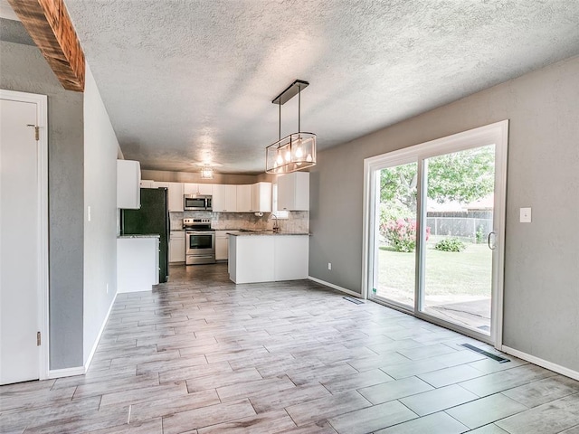 1917 Barryton Rd, Oklahoma City, OK 73120 - kitchen with stainless steel appliances, white cabinets, open floor plan, a chandelier, and a textured ceiling