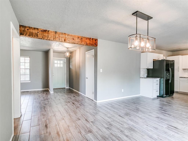 1917 Barryton Rd, Oklahoma City, OK 73120 - unfurnished living room featuring a textured ceiling, light wood finished floors, and a chandelier