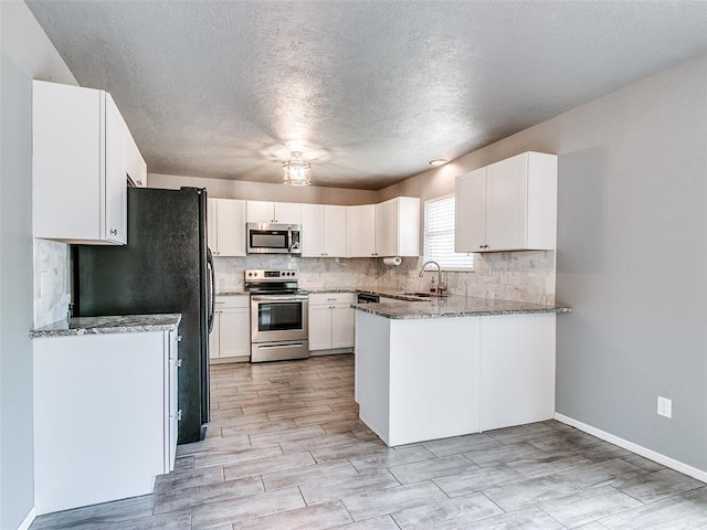 1917 Barryton Rd, Oklahoma City, OK 73120 - kitchen with appliances with stainless steel finishes, stone countertops, backsplash, white cabinetry, and a textured ceiling