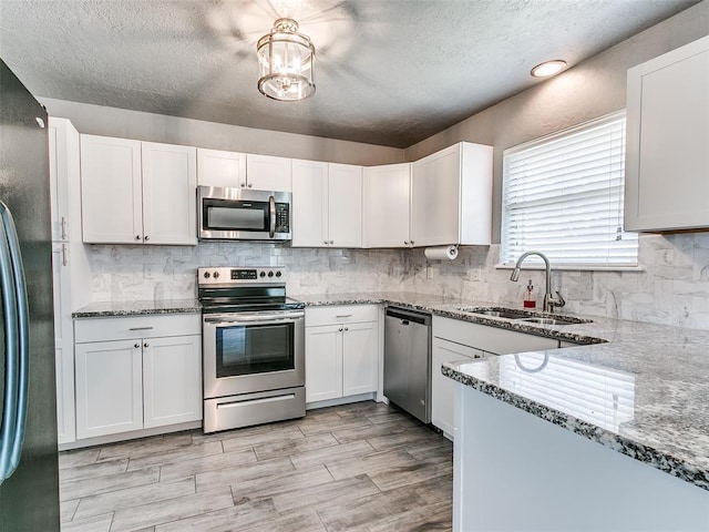 1917 Barryton Rd, Oklahoma City, OK 73120 - kitchen with appliances with stainless steel finishes, a textured ceiling, light stone counters, white cabinets, and decorative backsplash
