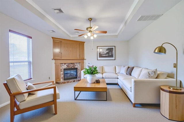 4621 Deer Ridge Blvd, Yukon, OK 73099 - living area featuring a ceiling fan, a raised ceiling, a glass covered fireplace, and light colored carpet