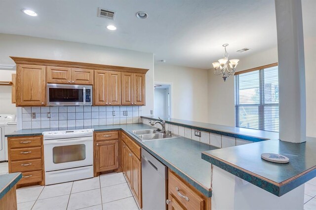 4621 Deer Ridge Blvd, Yukon, OK 73099 - kitchen featuring stainless steel appliances, washing machine and clothes dryer, a peninsula, dark countertops, and light tile patterned floors
