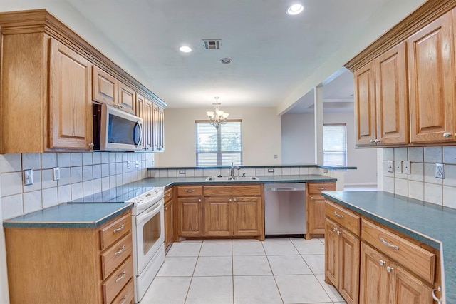 4621 Deer Ridge Blvd, Yukon, OK 73099 - kitchen with stainless steel appliances, dark countertops, a peninsula, tasteful backsplash, and a chandelier