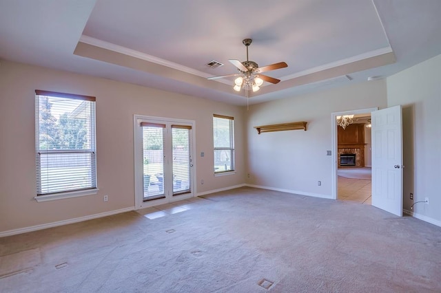 4621 Deer Ridge Blvd, Yukon, OK 73099 - spare room with a raised ceiling, ceiling fan, a fireplace, light colored carpet, and crown molding