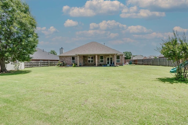 4621 Deer Ridge Blvd, Yukon, OK 73099 - back of house with a fenced backyard, brick siding, and a chimney